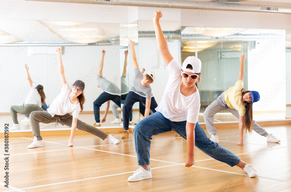 Obraz premium Positive teenage girls and boys training hip hop in dance studio, dance classes for teens
