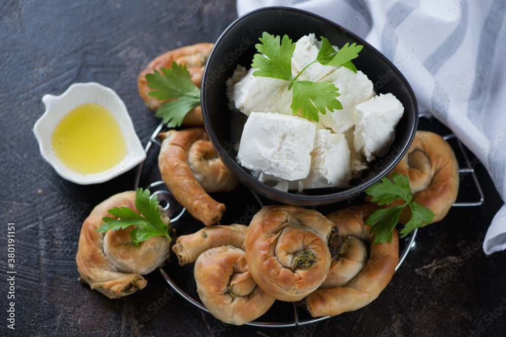 Bowl with chunks of feta and greek spinach and cheese spirals, horizontal shot on a dark brown stone background Bowl with chunks of feta and greek spinach and cheese spirals, horizontal shot on a dark brown stone background
