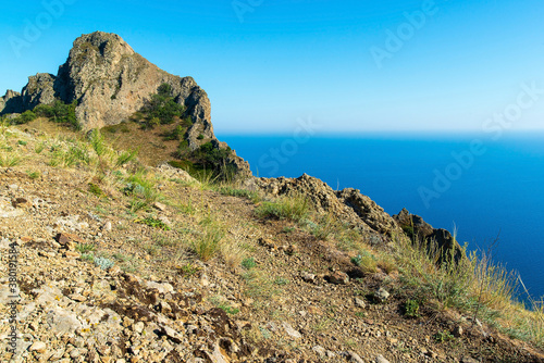 Rock of the Karadag reserve against the background of the bright blue sea, Crimea.