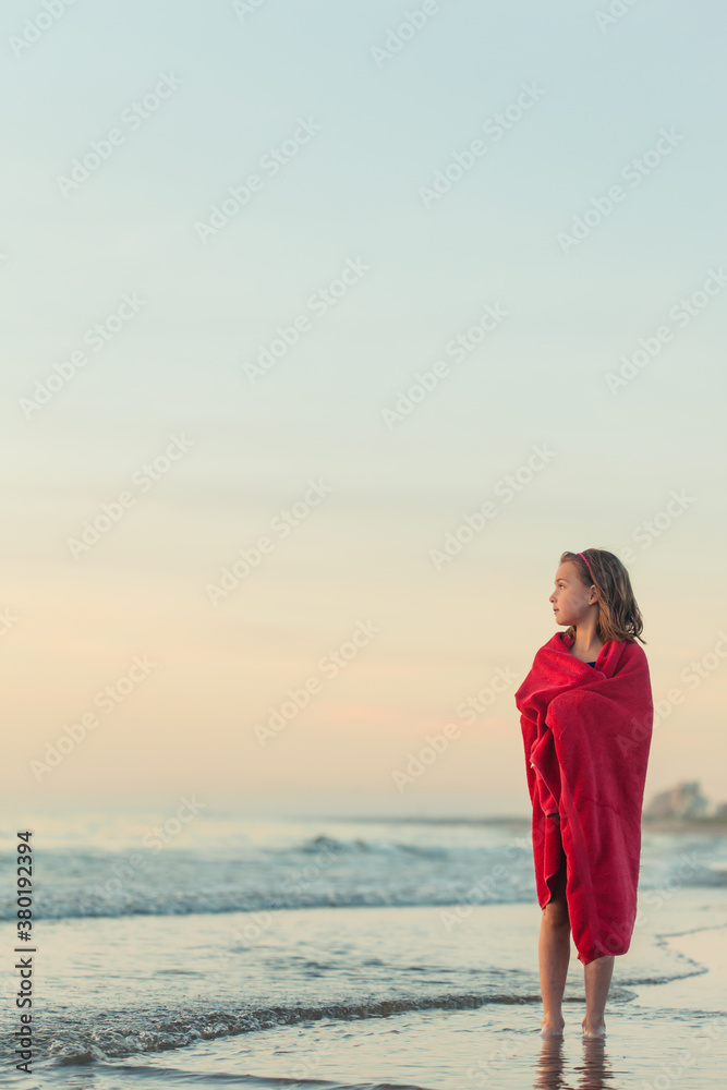 Little girl wrapped in red towel standing in the ocean Little girl wrapped in red towel standing in the ocean
