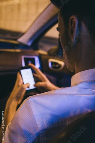 Young man waching his phone sitting on the passenger sit of a car photo