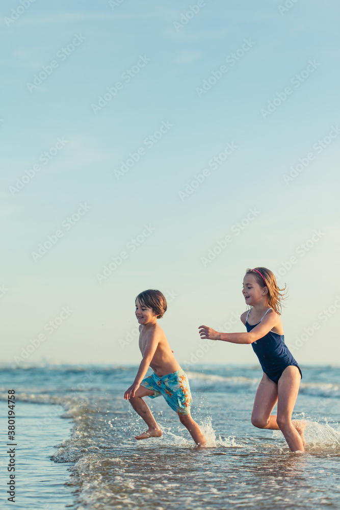 Smiling brother and sister running out of the ocean Smiling brother and sister running out of the ocean