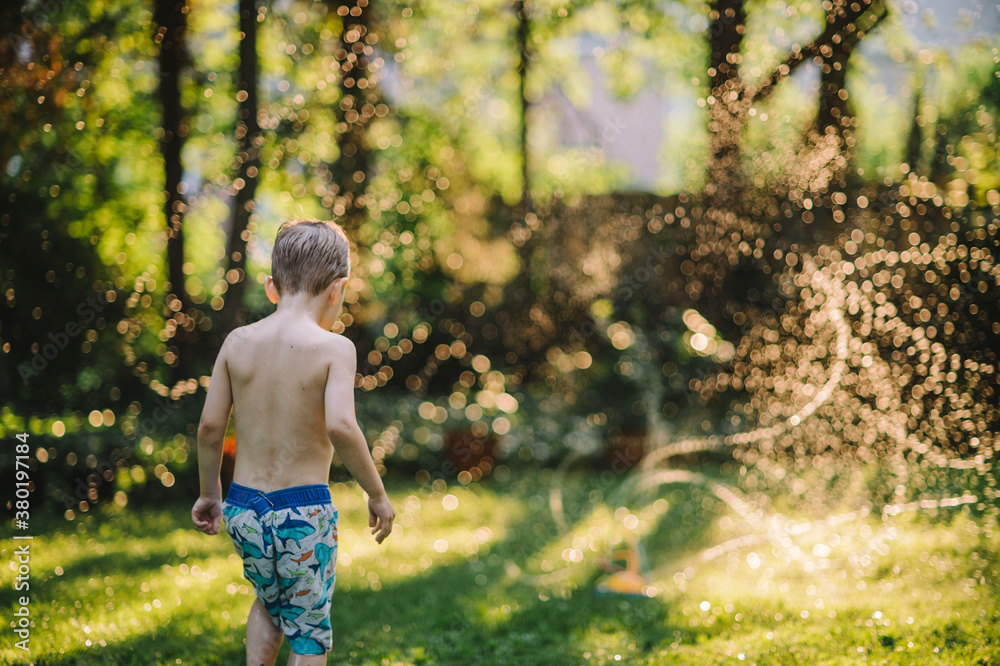 Little boy running through crazy sprinklers in the backyard Little boy running through crazy sprinklers in the backyard