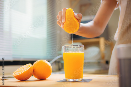 Bild auf Leinwand Woman hand squeezes juice from fresh orange, Homemade a glass of orange juice