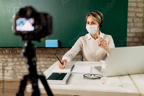 Female teacher holding online lesson from the classroom during coronavirus epidemic.