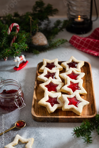 Christmas or New Year homemade sweet biscuits on wooden tray. Traditional Austrian christmas cookies - Linzer biscuits filled with red raspberry jam. Festive decoration. Homemade bakery