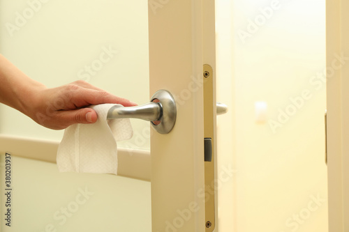 Woman hand using antibacterial wet wipe for disinfecting door handle