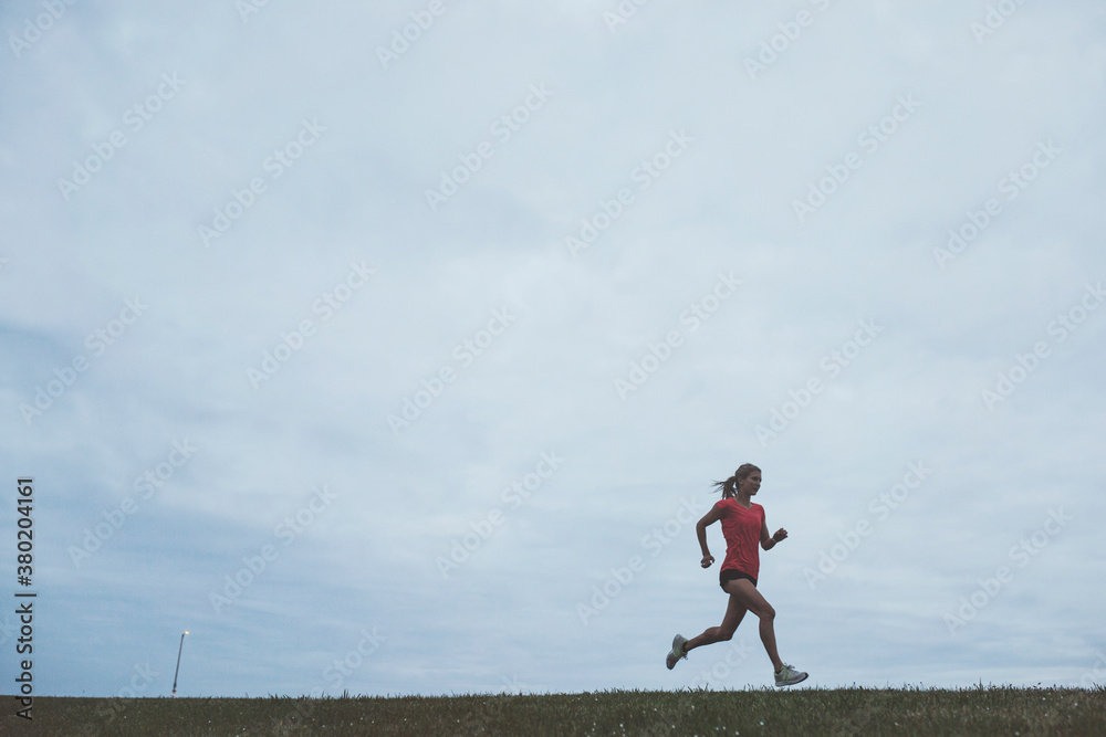 Motivated young woman running hard outside on cold windy day Motivated young woman running hard outside on cold windy day