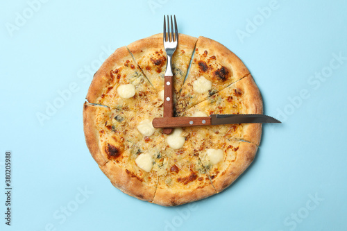 Clock made of pizza and cutlery on blue background