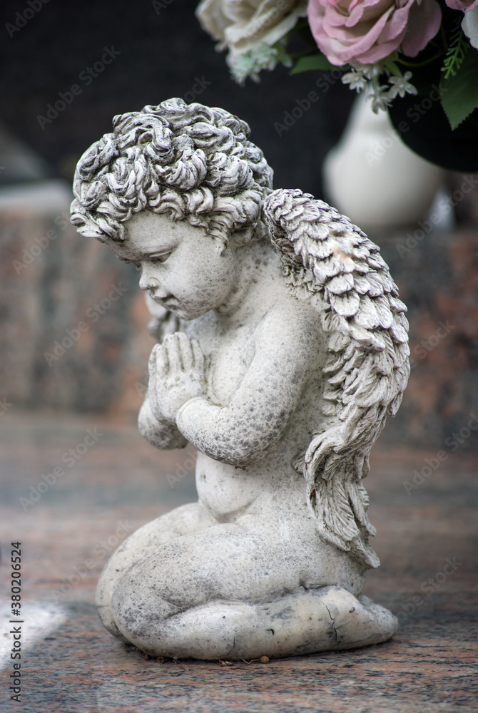 Closeup of stoned angel praying on tomb in a cemetery