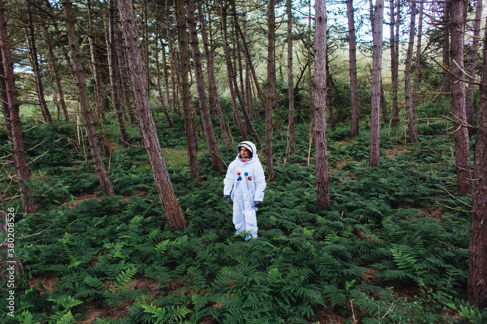A man in space suit standing in a forest. A man in space suit standing in a forest.