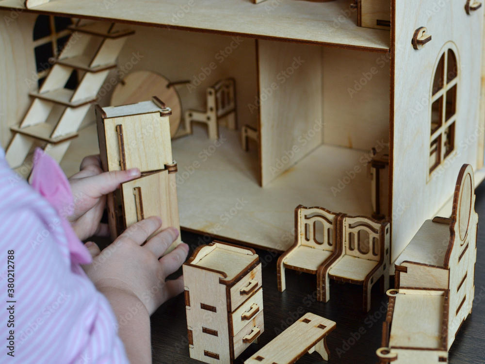 Little girl plays with a wooden doll house Little girl plays with a wooden doll house