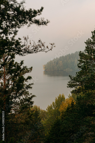 Scenic lake view with sunrise, island and foggy mood at beautiful autumn morning in Finland