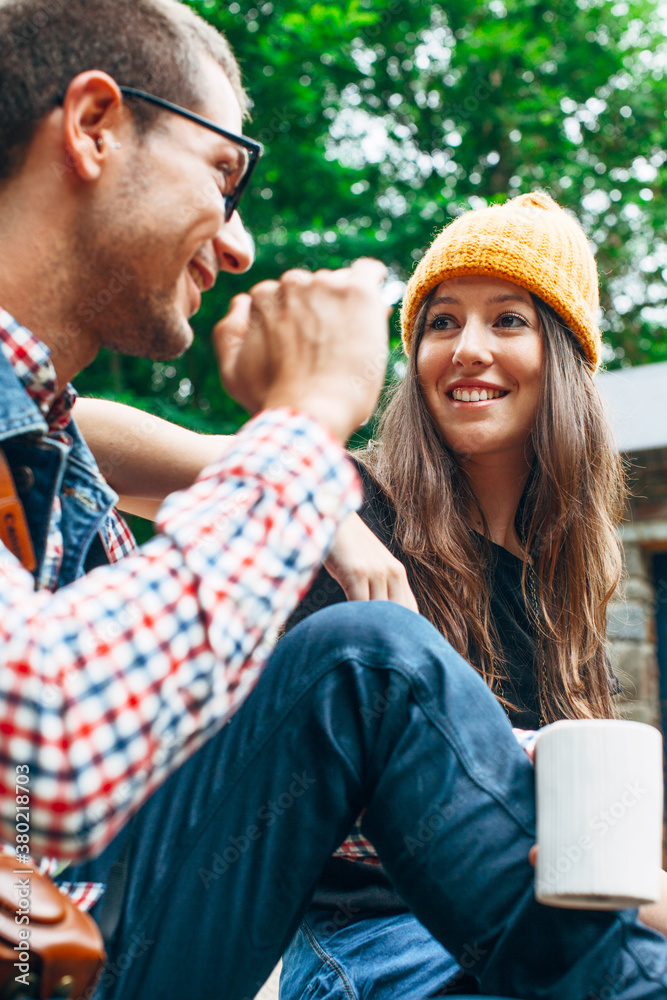Young smiling couple talking and drinking coffee on outdoors.