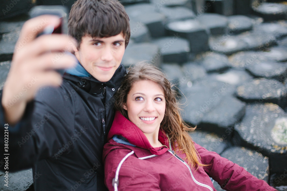 Young Couple Take Picture With Mobile Phone at Giant Causeway Young Couple Take Picture With Mobile Phone at Giant Causeway