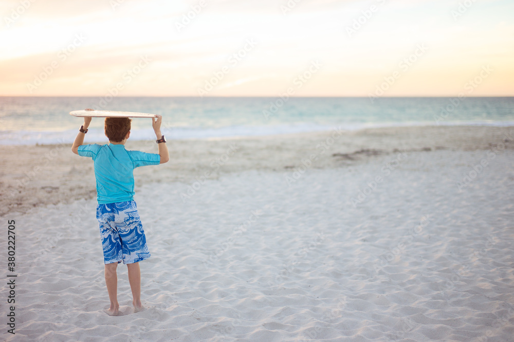 Boy with skim board on his head looks towards the ocean Boy with skim board on his head looks towards the ocean