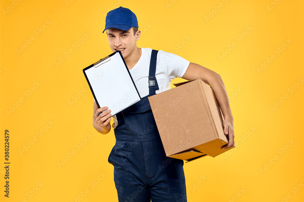 Working man in uniform with box hand delivery loading service yellow background