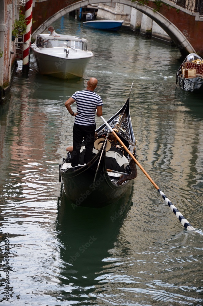 Gondolier in a gondola on a channel in Venice, Italy, a sunny day in autumn