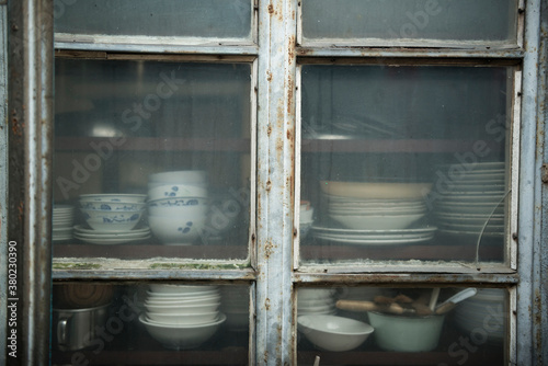 Dishes and piles of bowls in old wooden cupboard photo