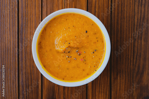 Hot spicy pumpkin soup in a bowl on wooden rustic background.