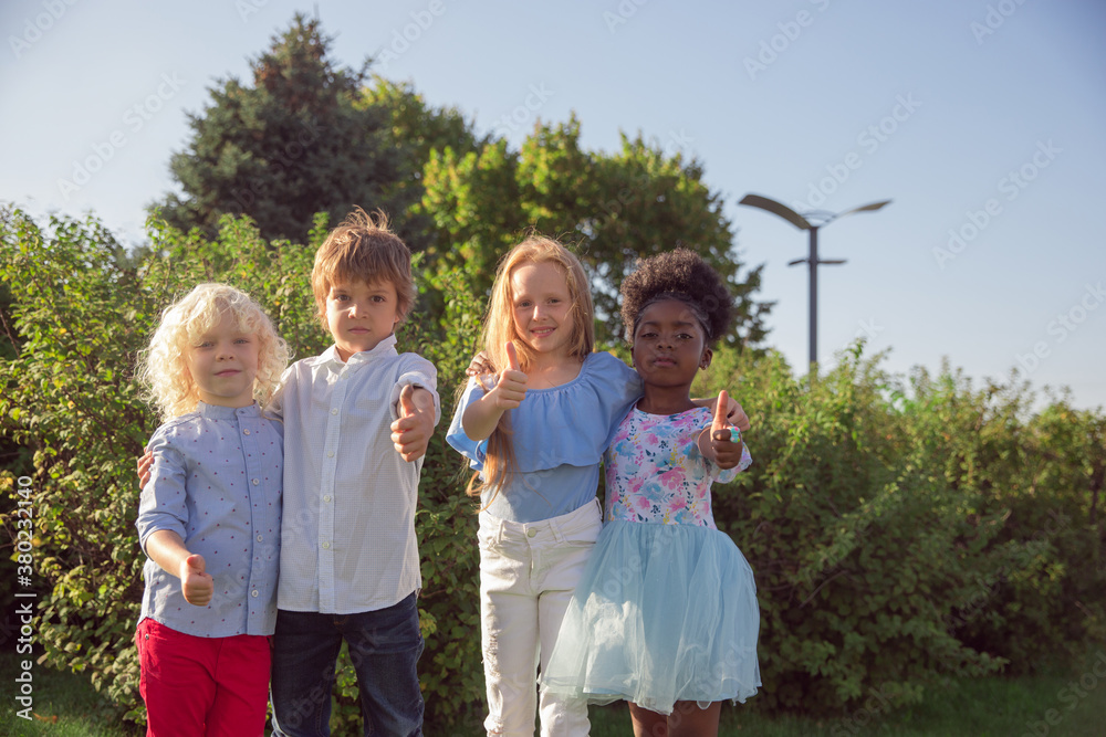 Fototapeta premium Together. Interracial group of kids, girls and boys playing together at the park in summer day. Friendship has no race. Happiness, childhood, education, diversity concept. Look happy and sincere.