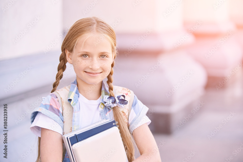 Beautiful american portrait of schoolgirl. Preschool kid. Little happy girl outdoors. Pretty female person. Adorable candid children. Near building. Holding book Beautiful american portrait of schoolgirl. Preschool kid. Little happy girl outdoors. Pretty female person. Adorable candid children. Near building. Holding book