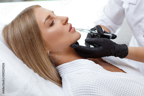 Enlarging lips, lip correction. Portrait white woman during an operation filling face wrinkles.
