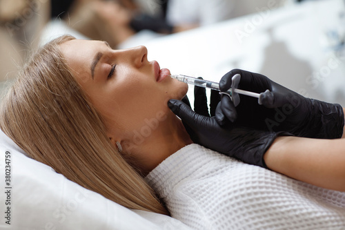 Enlarging lips, lip correction. Portrait white woman during an operation filling face wrinkles.
