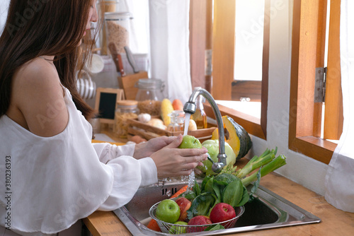 Woman's hands washing green apple to remove pesticides before cooking in kitchen under the tap