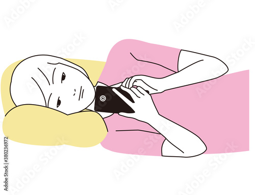 スマートフォンを寝転がって見つめる女性
