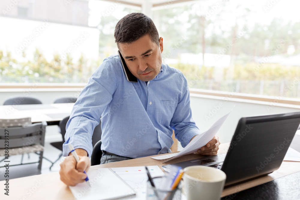 technology, remote job and business concept - middle-aged man calling on smartphone and writing to notebook at home office technology, remote job and business concept - middle-aged man calling on smartphone and writing to notebook at home office