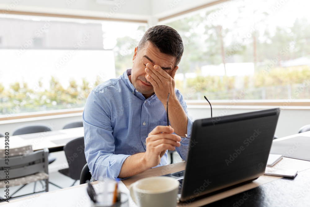 remote job, technology and business concept - tired middle-aged man with laptop computer and papers working at home office remote job, technology and business concept - tired middle-aged man with laptop computer and papers working at home office