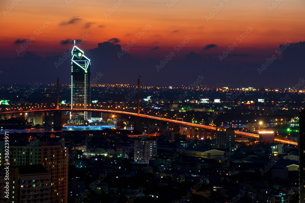 Obraz premium Long-speed photograph of the Industrial Ring Expressway and Bhumibol Bridge. Cityscape Bangkok at night, buildings in the central business district.