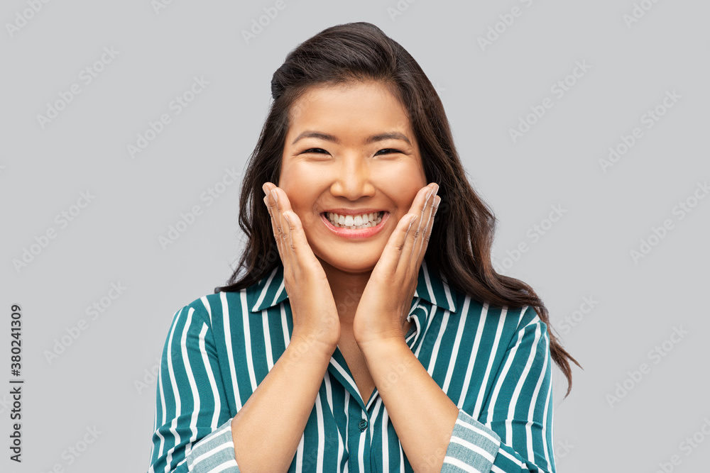 people, gesture and emotion concept - happy asian young woman over grey background people, gesture and emotion concept - happy asian young woman over grey background