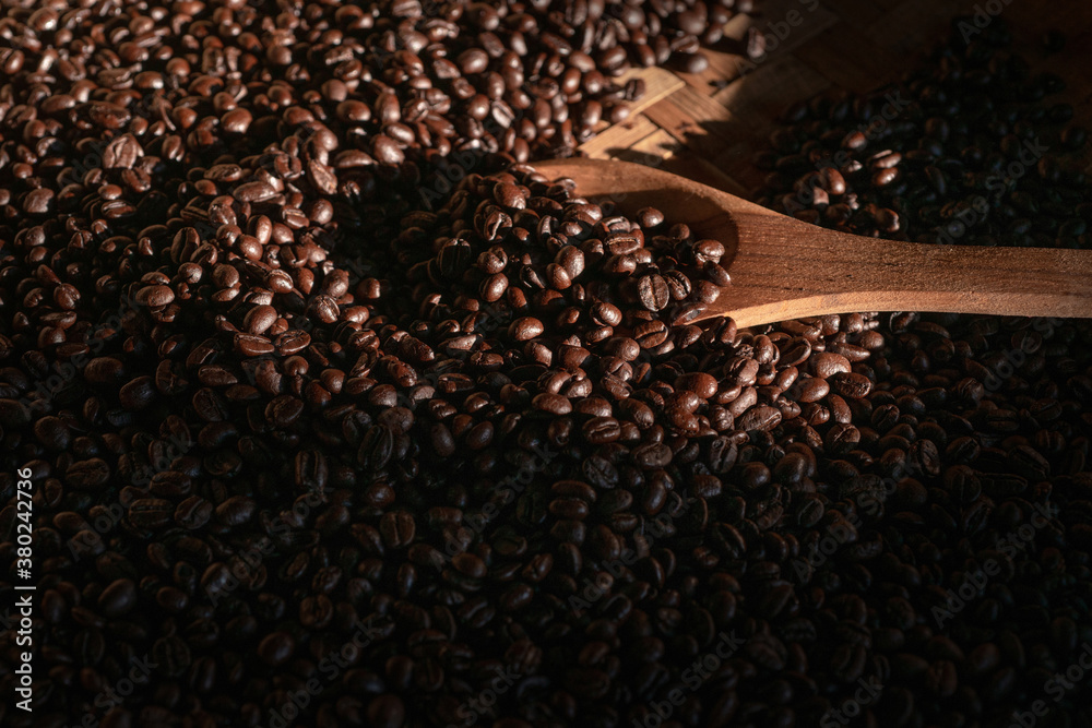 Coffee beans in wooden spoon, under beam of light Coffee beans in wooden spoon, under beam of light