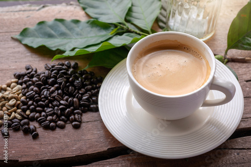 Coffee cup  coffee beans decorated with coffee leaves on wooden table .top view