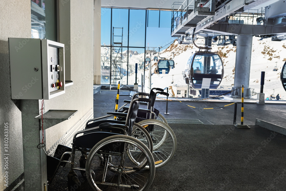 Many empty wheelchairs prepared for disabled people at station of cabin gondola ski lift at mountain alpine luxury austrian winter resort. Handicapped person friendly care service