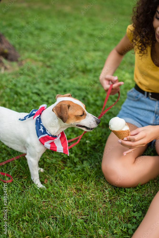 Cropped view of young woman keeping dog on leash and holding ice cream Cropped view of young woman keeping dog on leash and holding ice cream