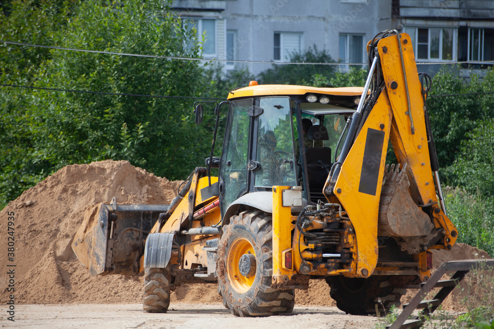An excavator at a construction site loads sand. An excavator at a construction site loads sand.