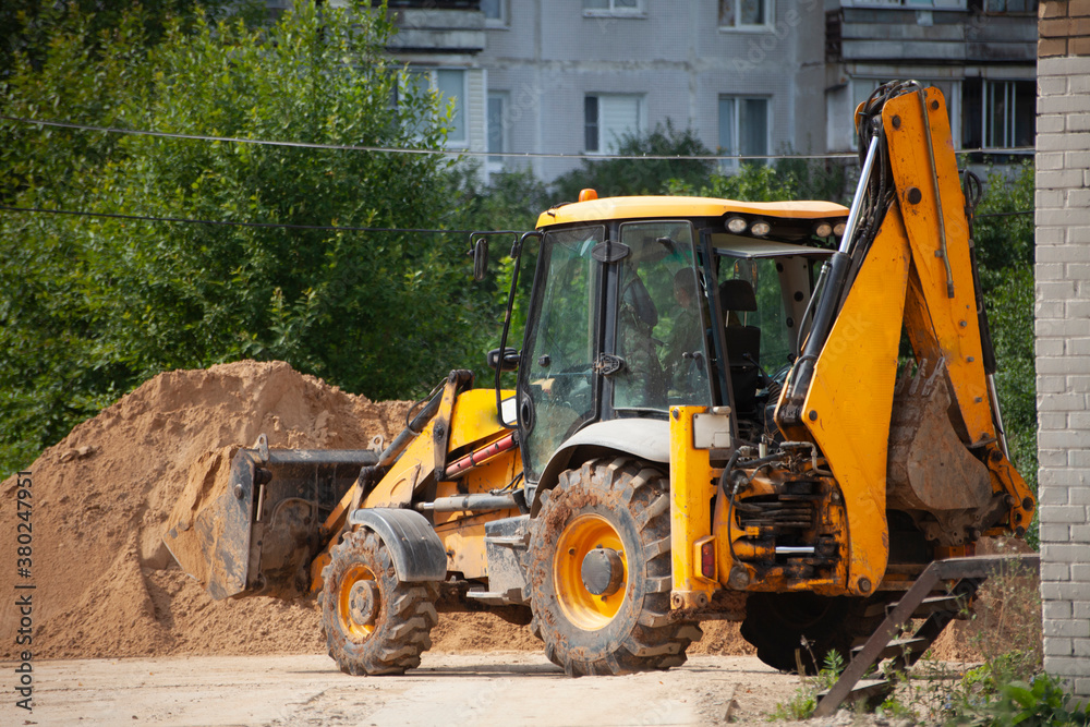 An excavator at a construction site loads sand. An excavator at a construction site loads sand.