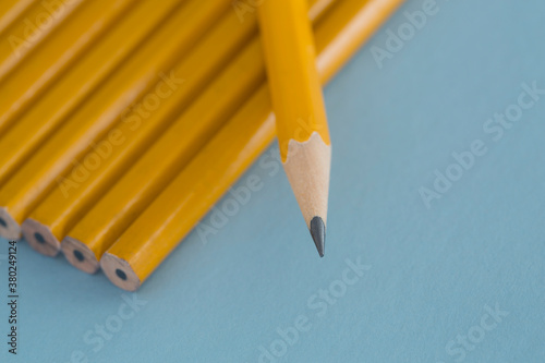Close-up of a sharpened yellow pencil lying on unsharpened pencils