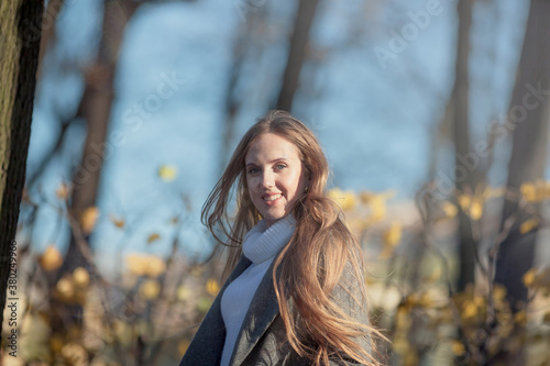 Pretty woman with light brown hair. Portrait of a beautiful smiling woman in an elegant gray coat. Happy young woman walks in the autumn park.