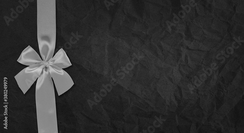 Gray ribbon with bow on textured black background. Black friday concept.