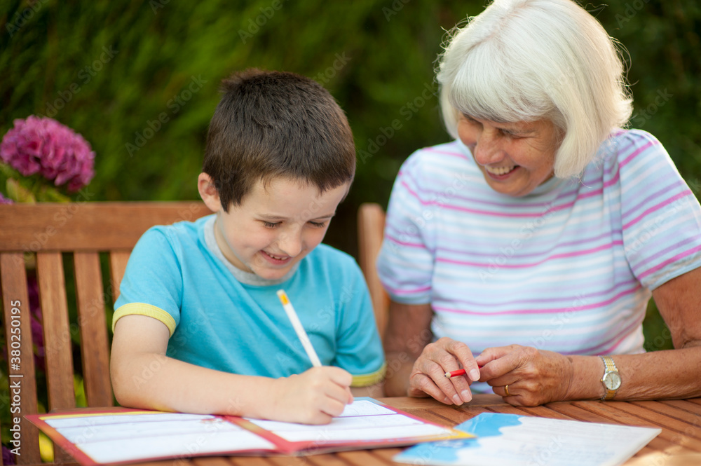 senior woman helping a young boy with his school work senior woman helping a young boy with his school work
