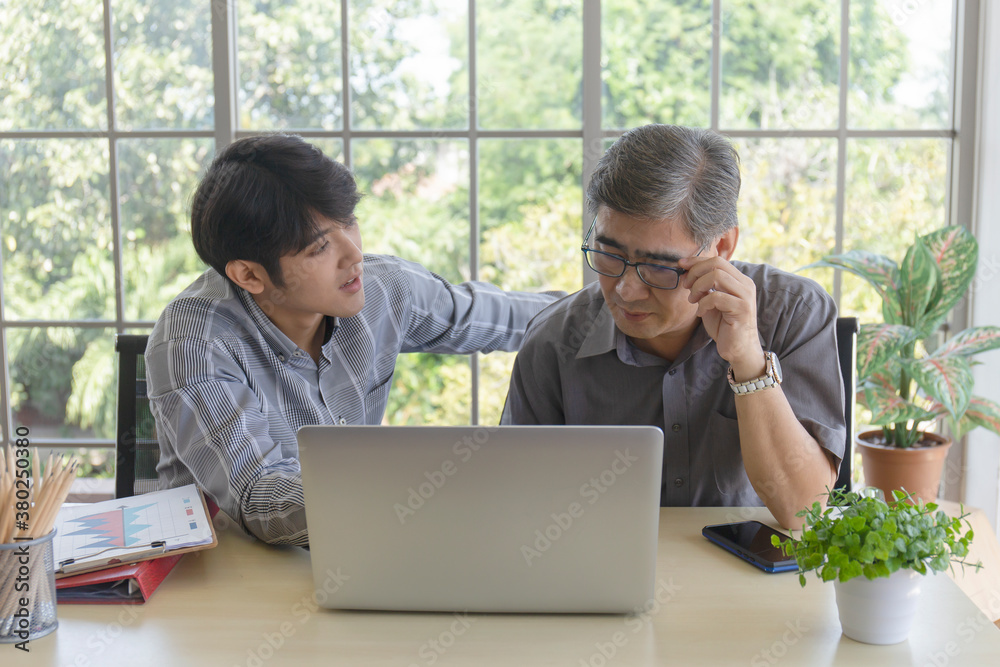 An elderly Asian man is learning how to trade online through the Internet with a young man who teaches him. An elderly Asian man is learning how to trade online through the Internet with a young man who teaches him.