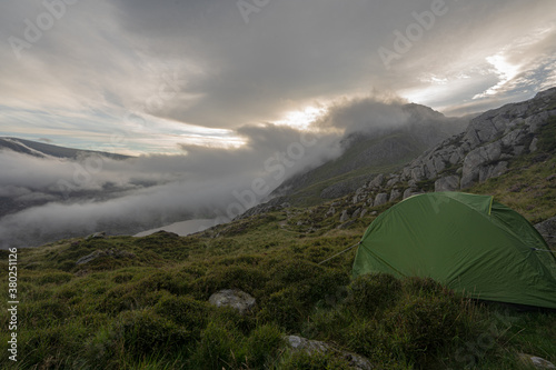 Wild camping tent in mountain wilderness with spectacular low cloud formation