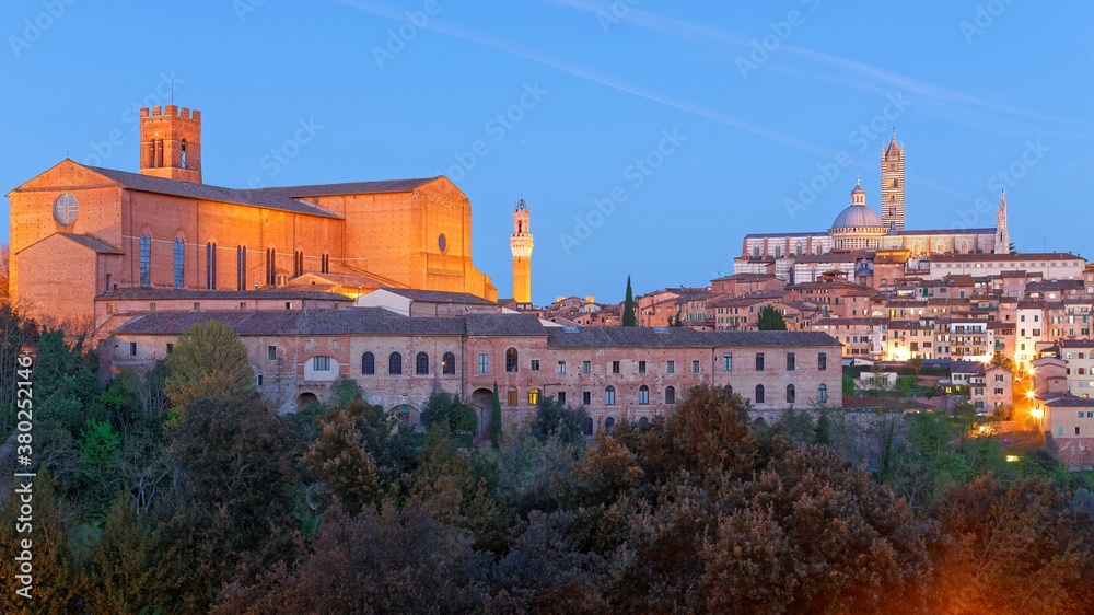 Night scenery of Siena, a medieval town in Tuscany Italy, with view of the Dome & Bell Tower of Siena Cathedral ( Duomo di Siena ) and landmark Mangia Tower ( Torre del Mangia ) in evening twilight