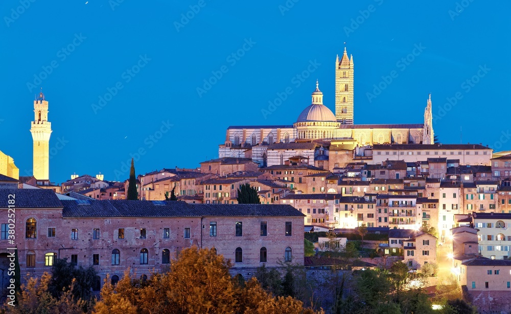 Night scenery of Siena, a medieval town in Tuscany Italy, with view of the Dome & Bell Tower of Siena Cathedral ( Duomo di Siena ) and landmark Mangia Tower ( Torre del Mangia ) in evening twilight