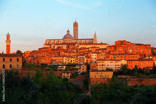 Sunset scenery of Siena, a beautiful medieval town on a hilltop in Tuscany Italy, with a view of architectural landmarks, Mangia Tower, Duomo Dome & Bell Tower bathed in warm, golden sunlight