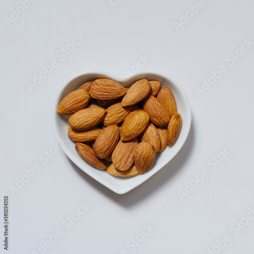 Raw almonds in heart shaped dish photo